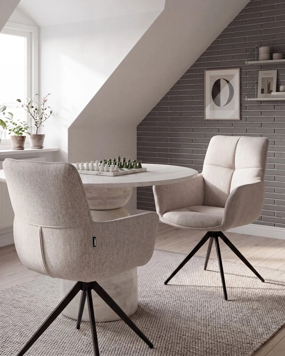 A modern dining room scene featuring two upholstered swivel chairs in a light beige textured fabric with black metal tripod bases, arranged around a round white table on a woven rug.