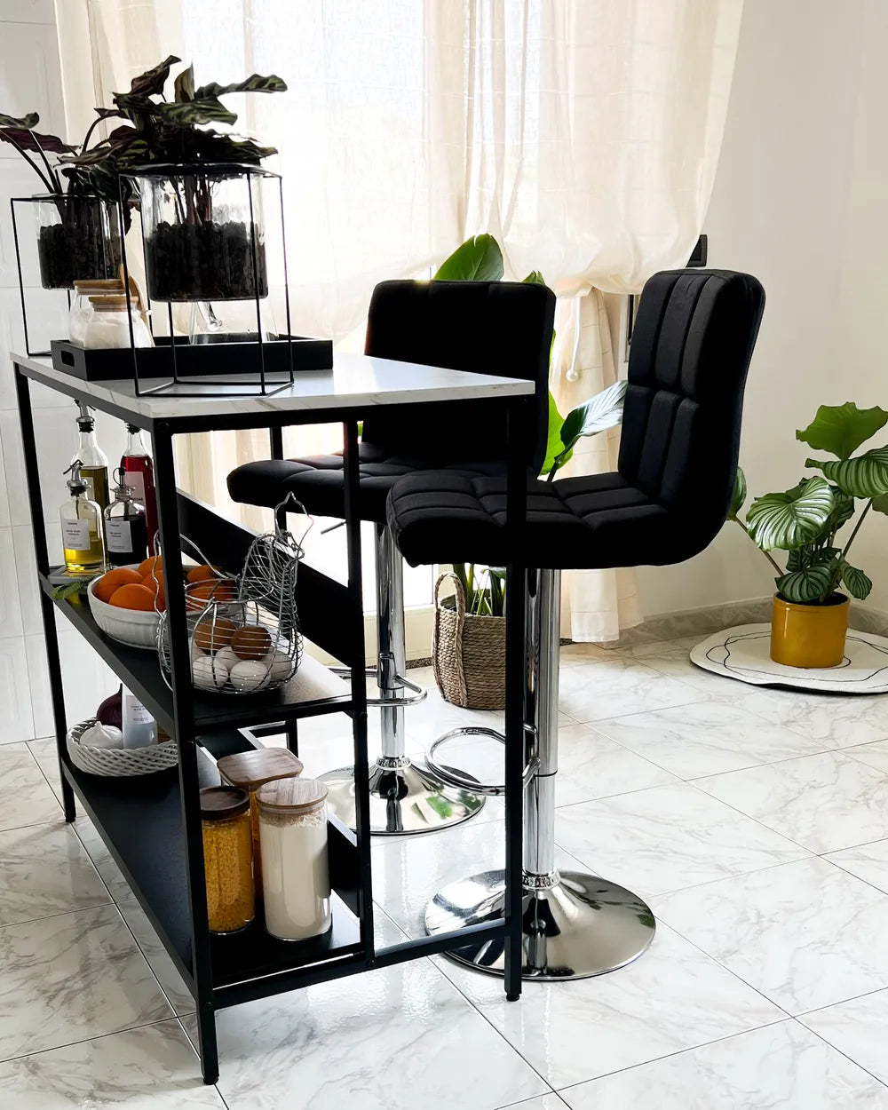 Black bar stools in front of a tall black shelf with various items in a room.
