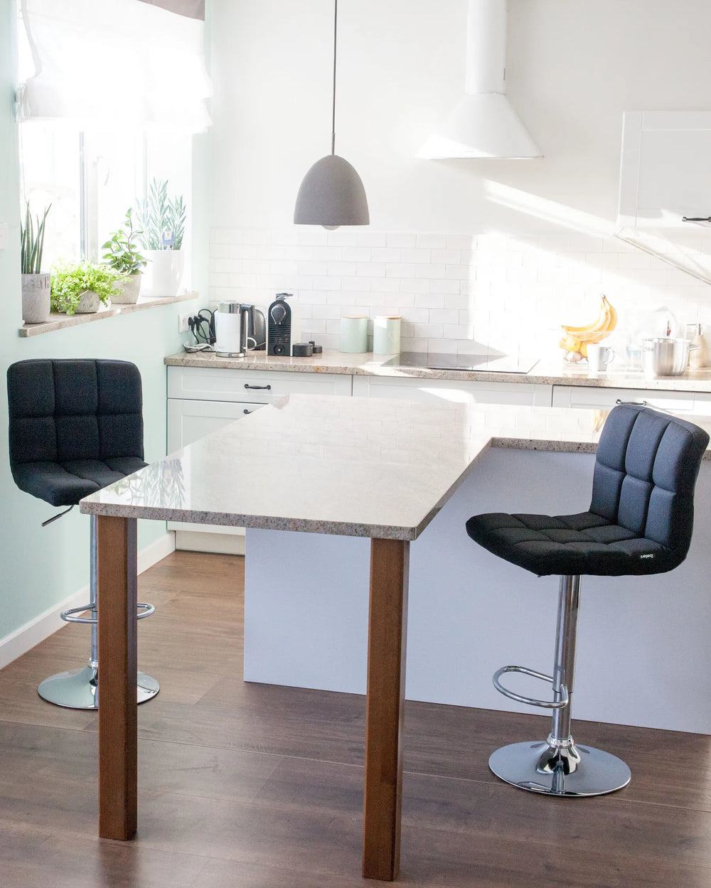 Modern kitchen with a white island and black bar stools.