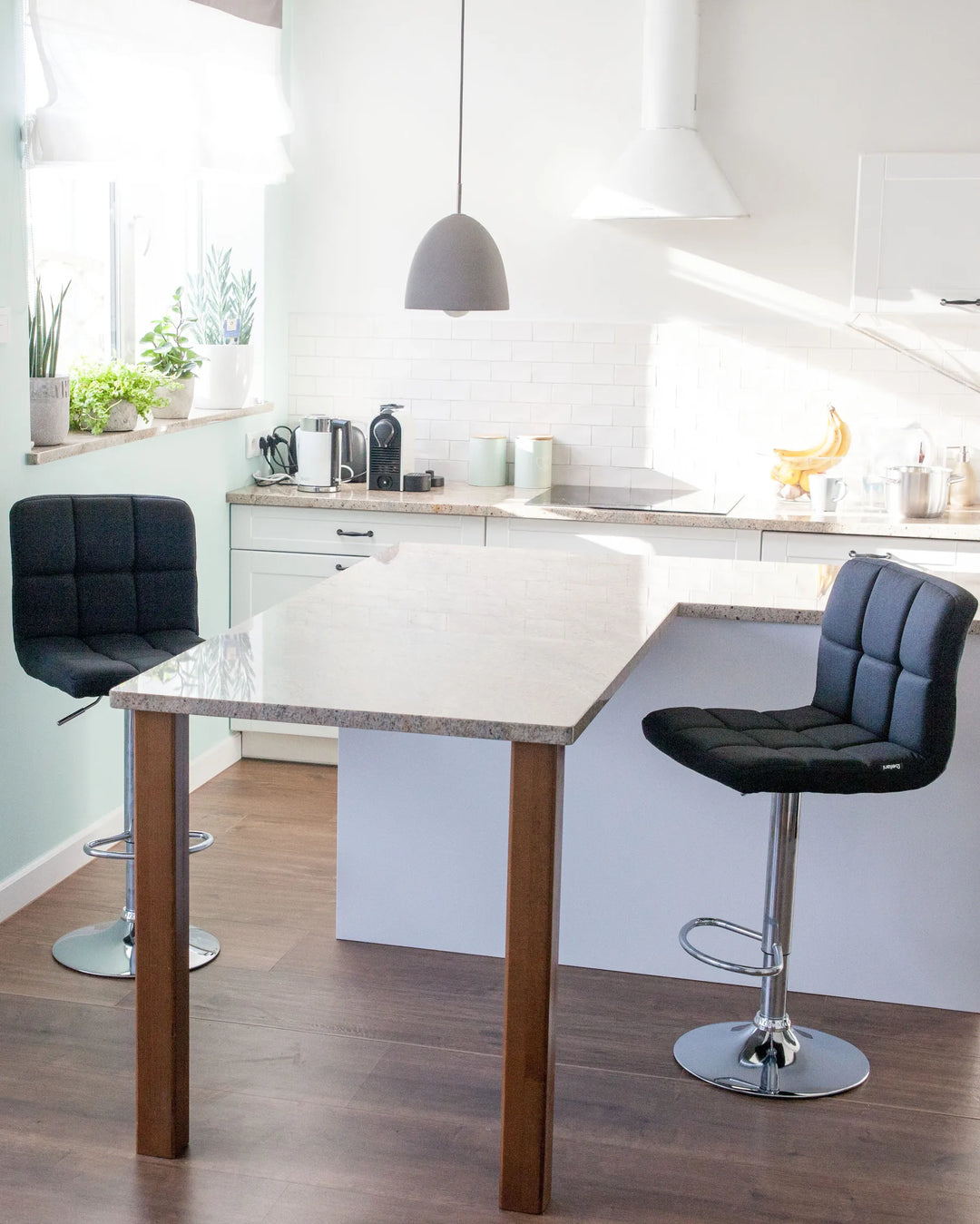 Modern kitchen with a white island and black bar stools.