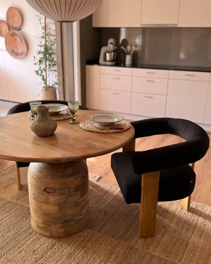 Wooden dining table with black chairs in a modern kitchen setting