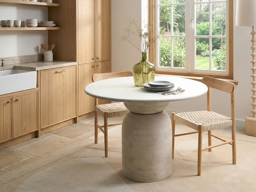 Modern kitchen with a round dining table and wooden chairs.
