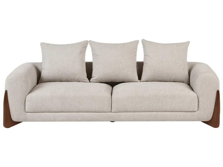 A modern three-seat sofa with light beige textured upholstery, three matching back cushions, and dark brown wooden legs, shown against a plain white background.