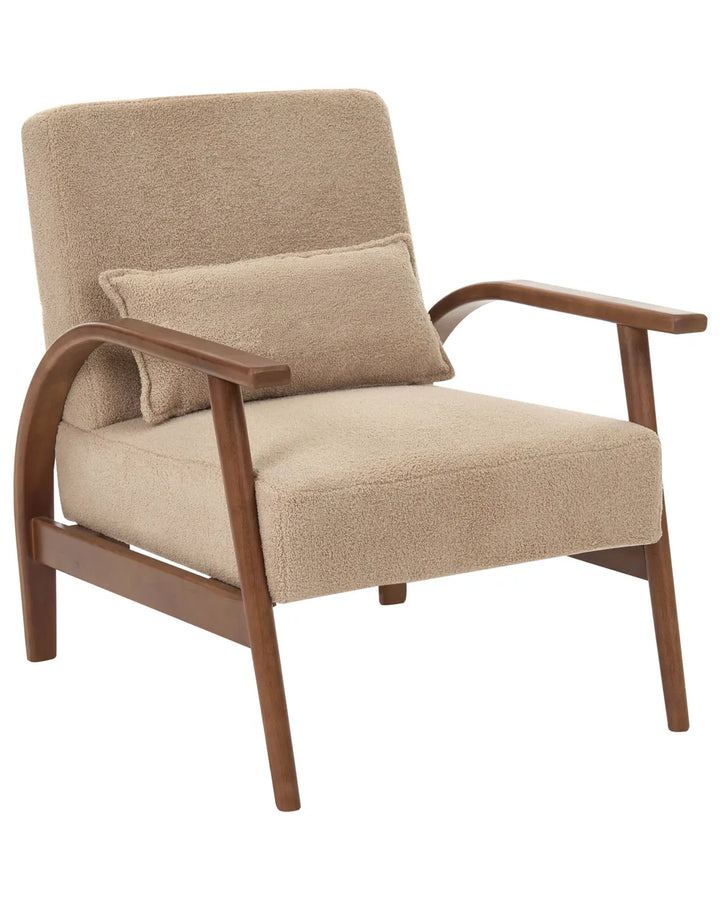 A mid-century modern armchair with beige bouclé upholstery and a matching lumbar pillow, featuring a curved medium-brown wooden frame.