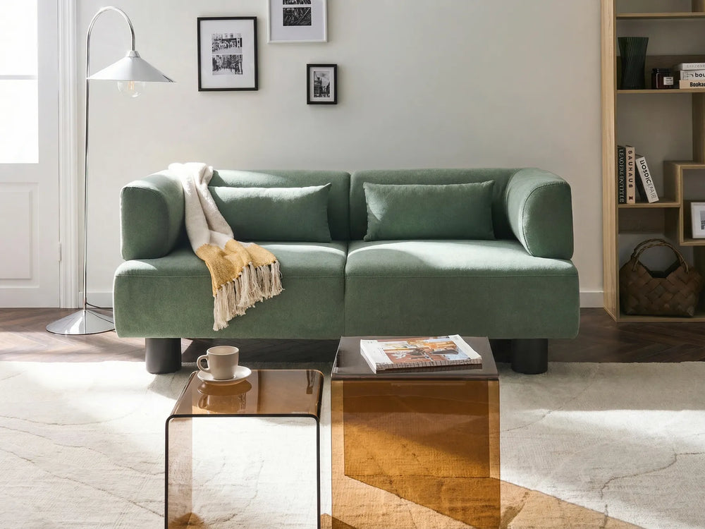 Green sofa in a living room with a coffee table and decor items.