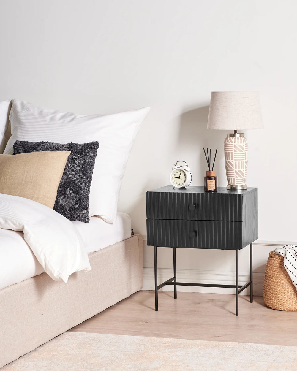 Black nightstand with decorative items next to a bed in a bedroom setting