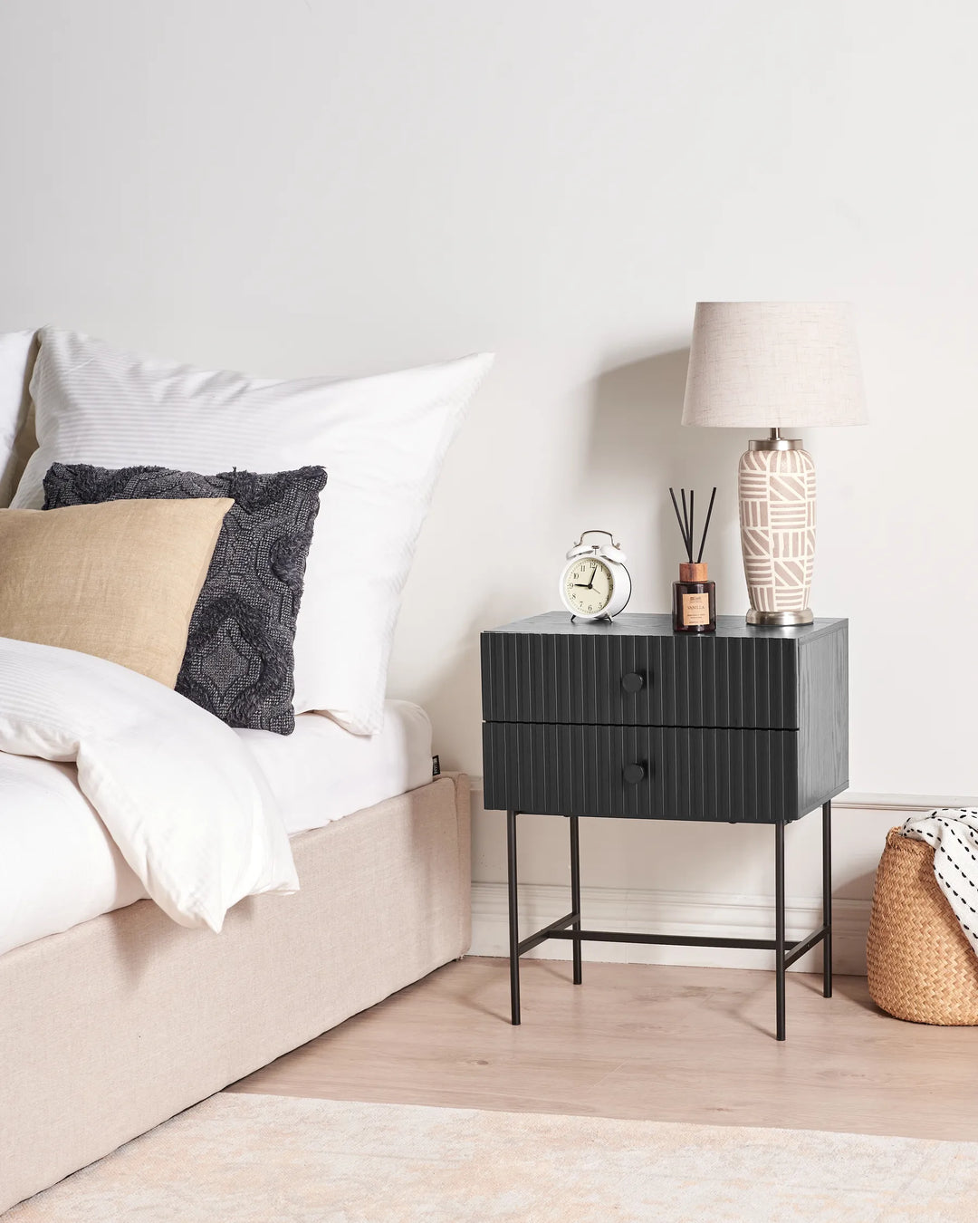 Black nightstand with decorative items next to a bed in a bedroom setting