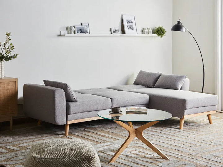 Modern living room with a gray sectional sofa, wooden coffee table, and decorative items.