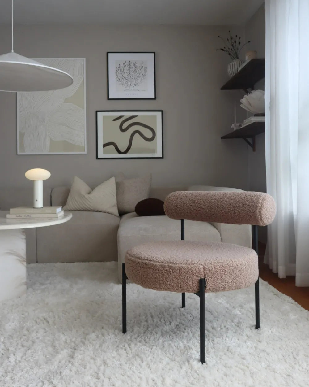 Modern living room with a beige sofa, round ottoman, and abstract art on the wall.