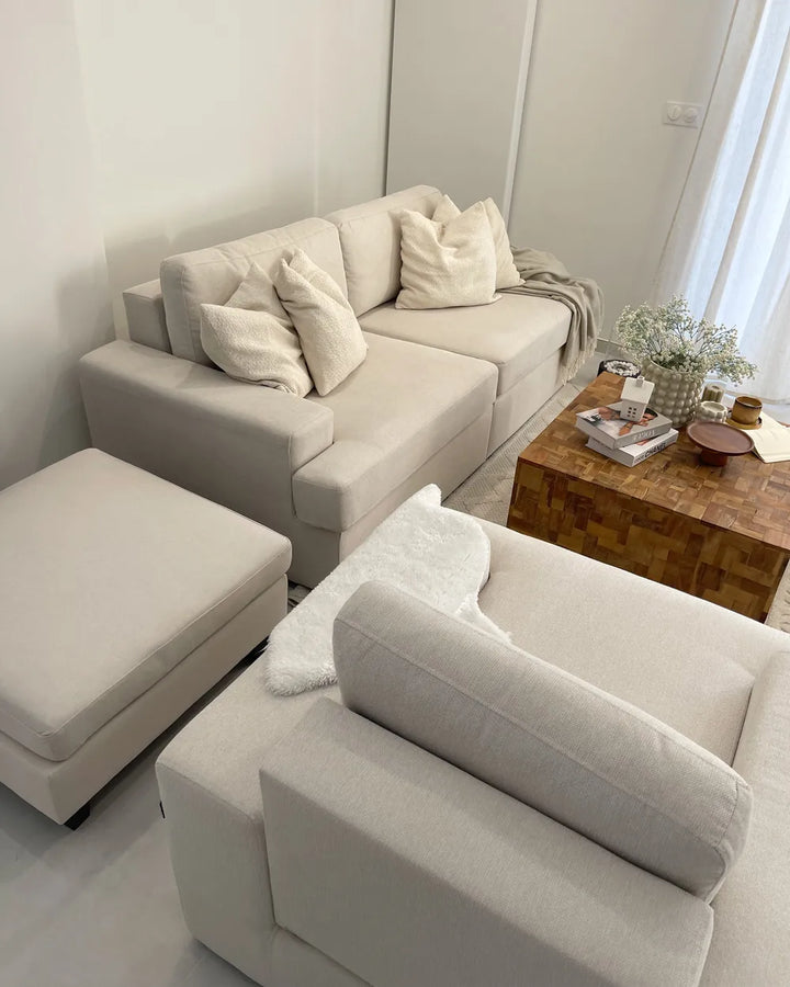 Beige sectional sofa with cushions in a living room setting.