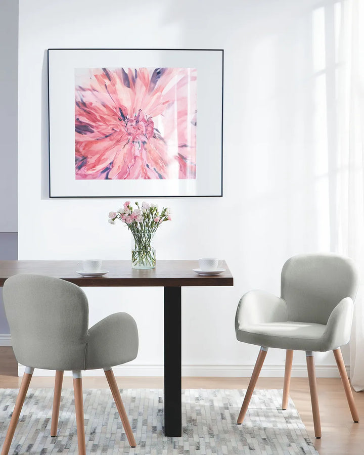 Dining area with a table and chairs, and a pink abstract painting on the wall.