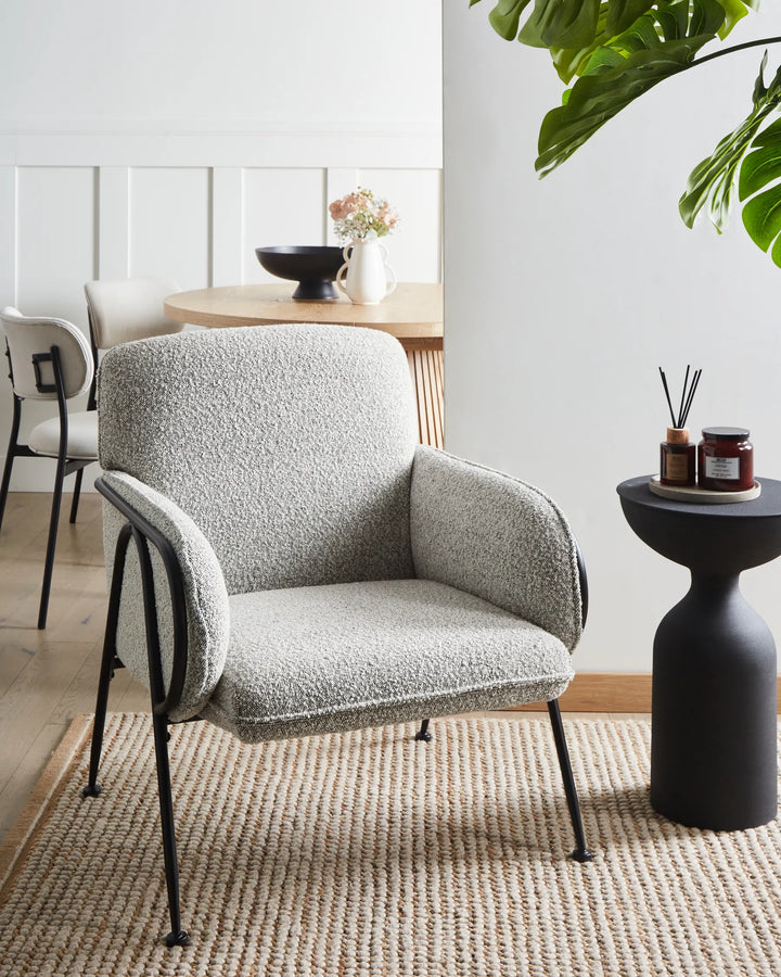 Gray armchair in a modern living room with a small table and decorative items.