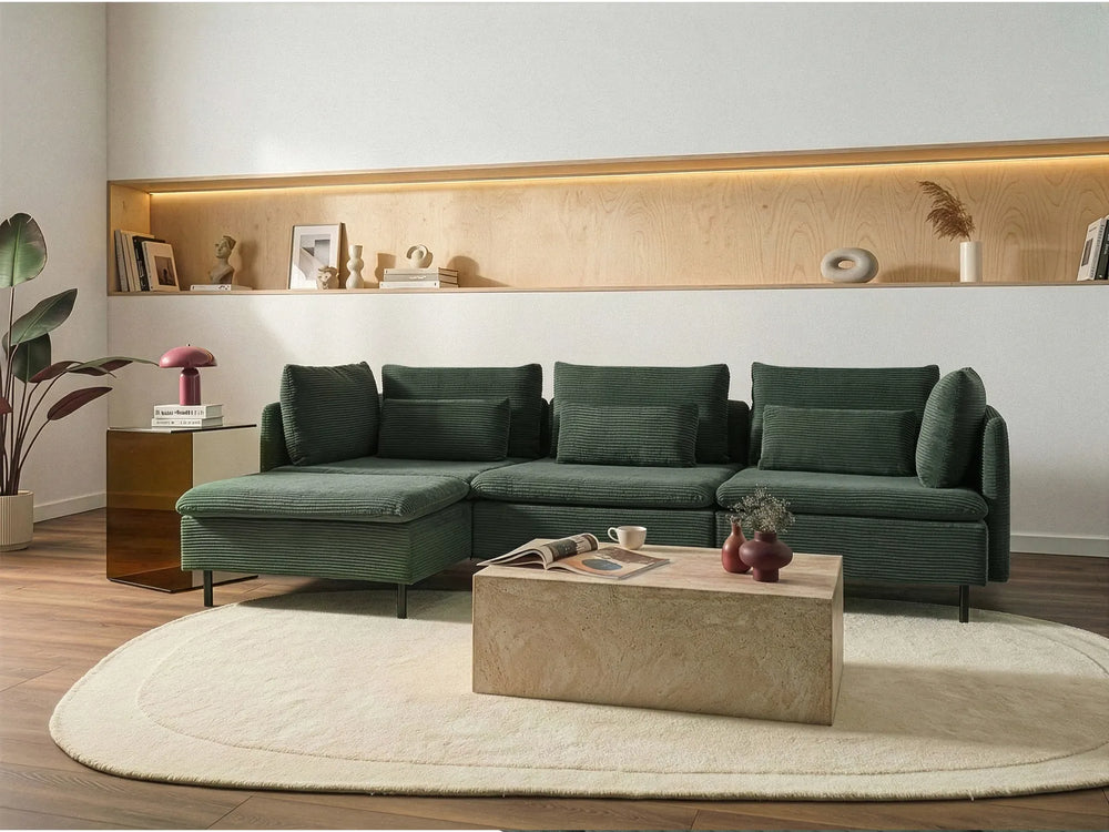 Modern living room with a green sectional sofa, coffee table, and decorative items.