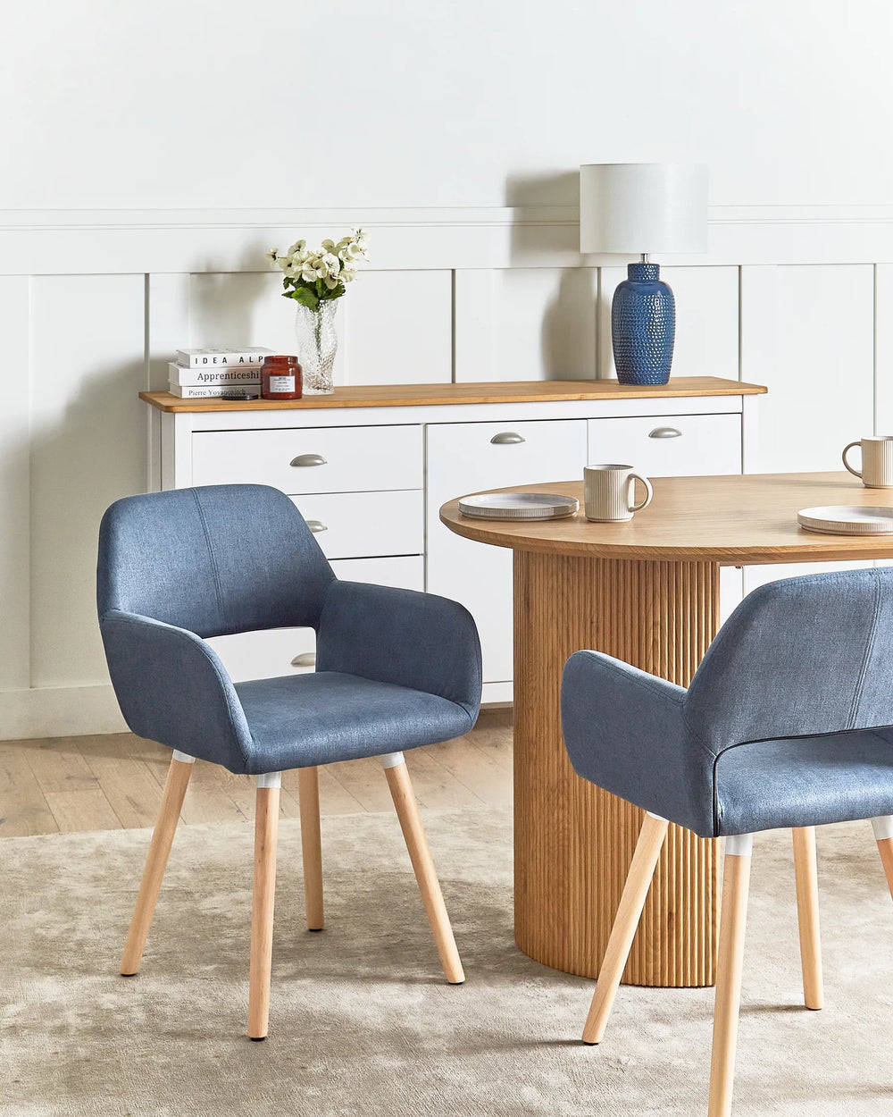 Two blue chairs in a room with a wooden table and white cabinets.