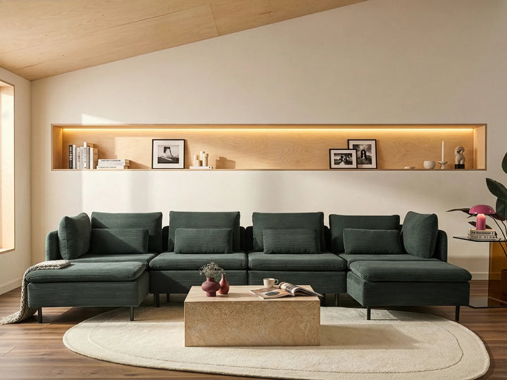 Modern living room with a dark green sectional sofa, wooden coffee table, and wall-mounted shelves.