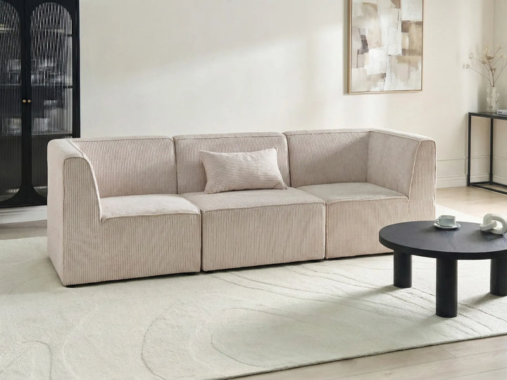 Beige sofa in a modern living room with a coffee table and abstract art on the wall.