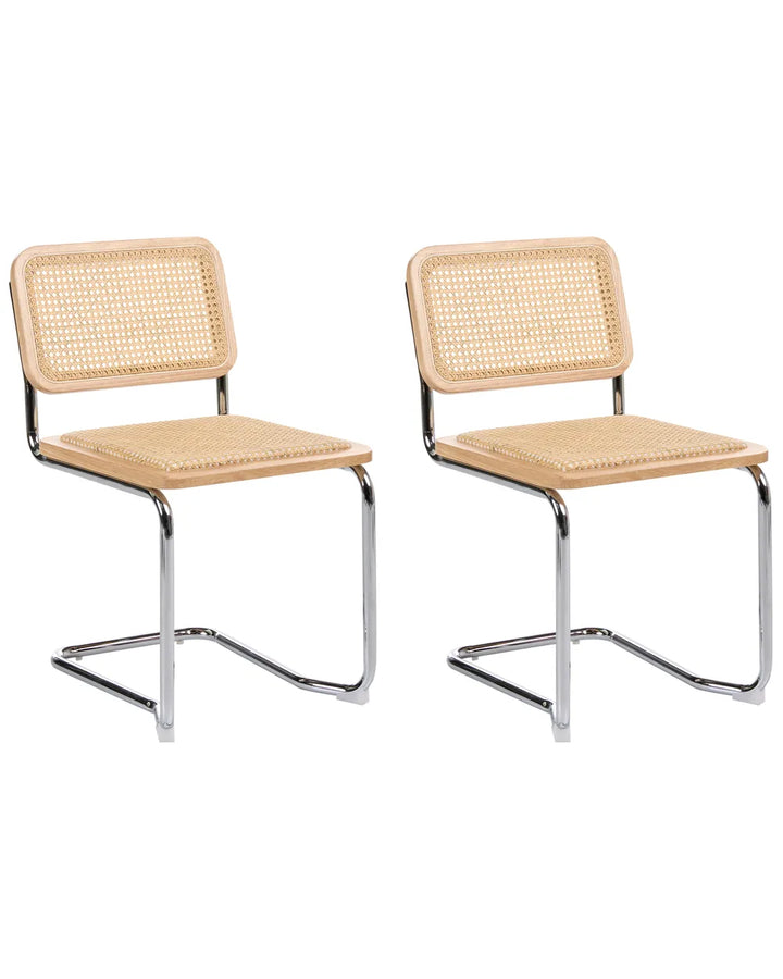 Two matching cantilever dining chairs with woven cane seats and backs on a plain white background.