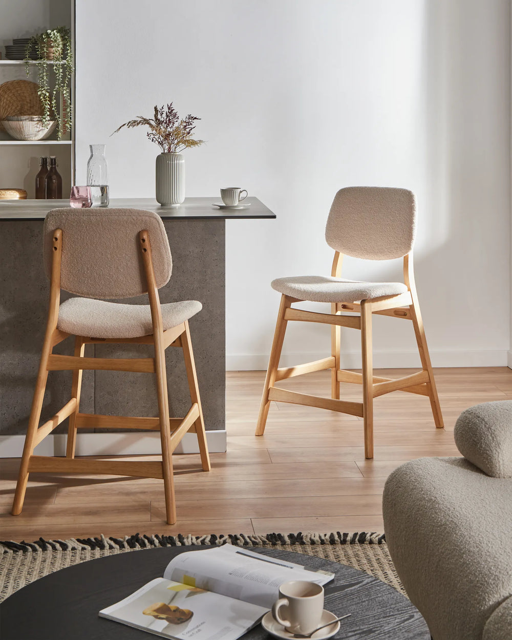 Two wooden bar stools in a modern kitchen setting with a table and decor.