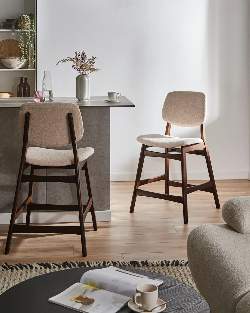 Two bar stools with wooden legs and beige cushioned seats in a modern kitchen setting.