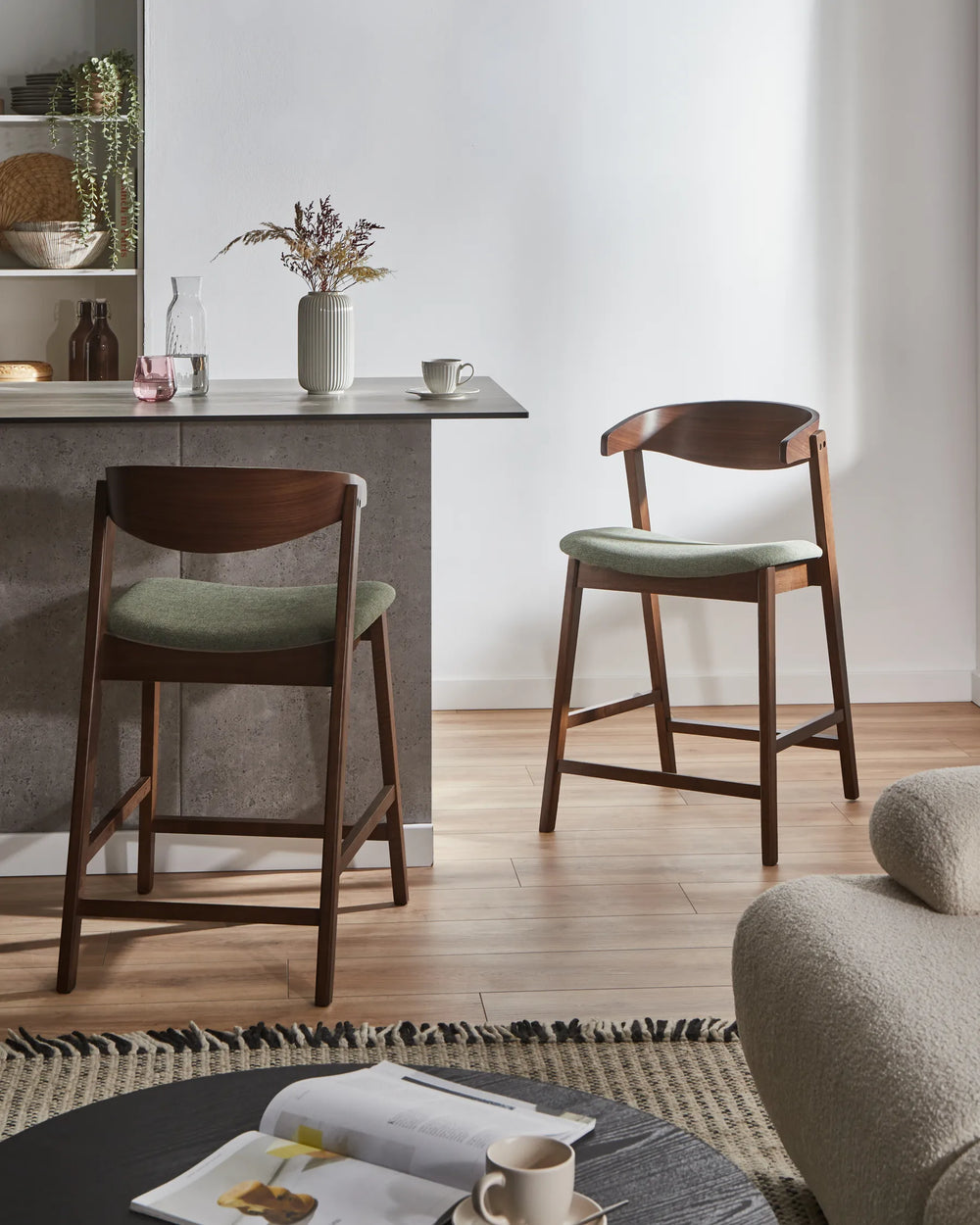 Two wooden bar stools with green cushions in a modern kitchen setting.
