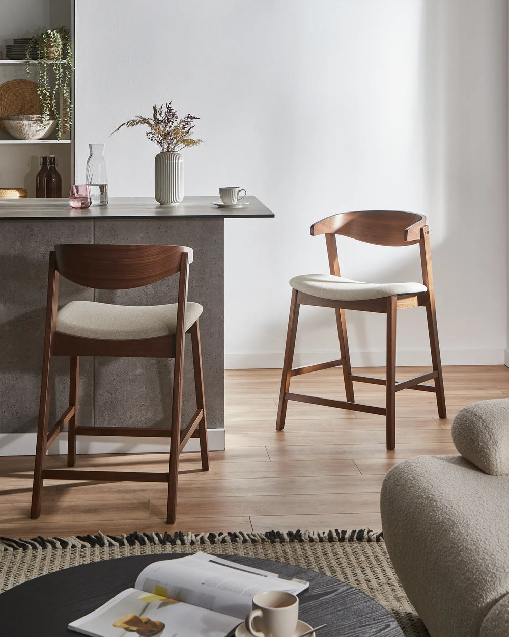 Two wooden bar stools with white seats in a modern kitchen setting.