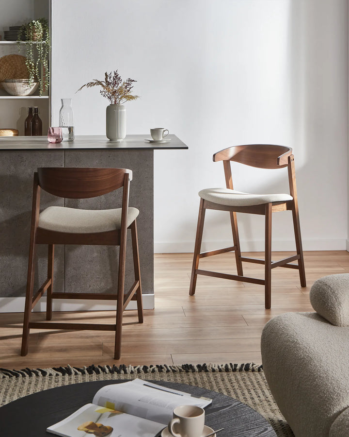 Two wooden bar stools with white seats in a modern kitchen setting.