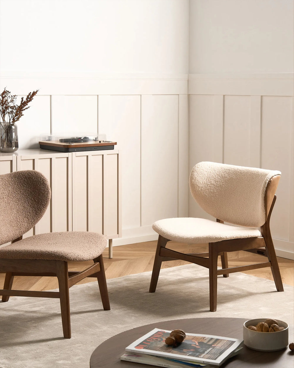 Two beige cushioned chairs in a room with a light-colored wall and wooden floor.