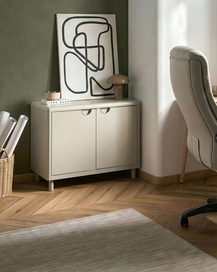 Beige sideboard with abstract art in a room with a chair and basket.
