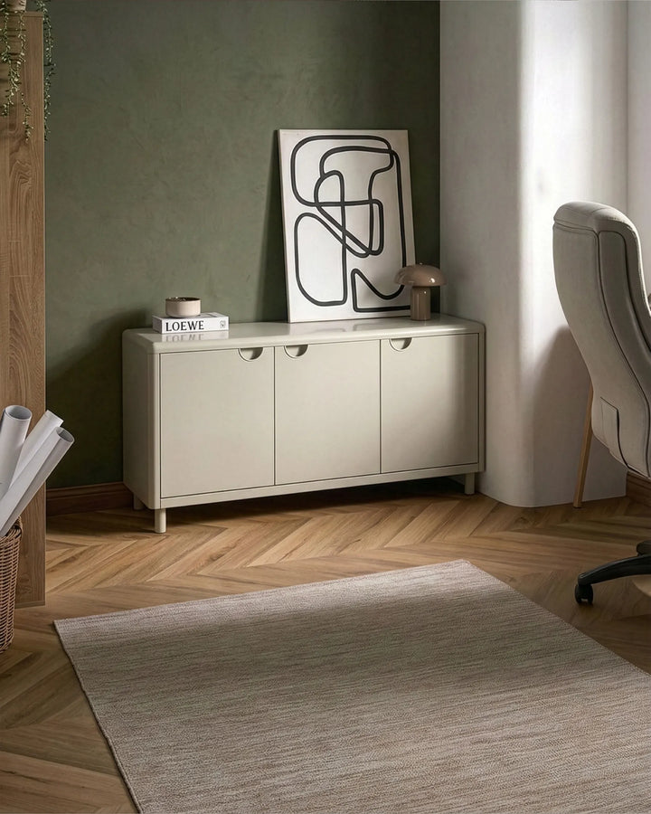 Beige sideboard with abstract art in a room with a rug and chair.