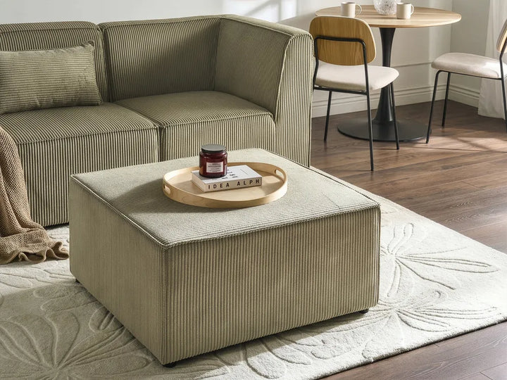 Beige sofa and ottoman with a tray on a rug in a living room setting
