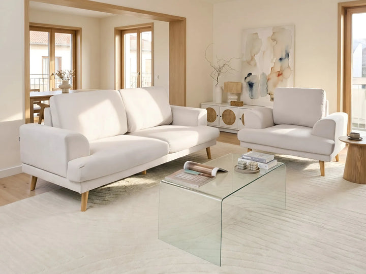 Modern living room with white sofa, glass coffee table, and decorative items.