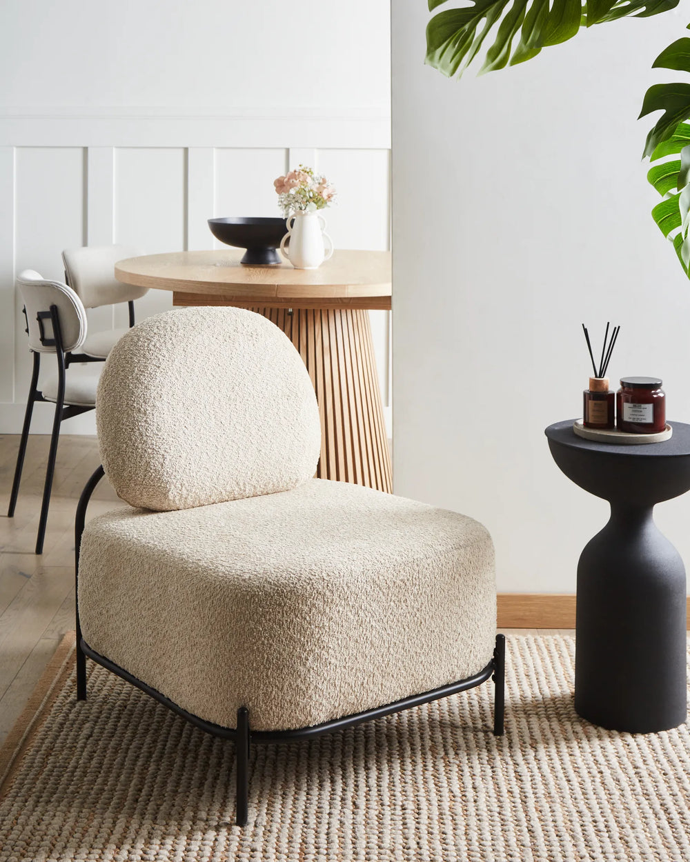Beige armchair in a modern interior setting with a table and plants.