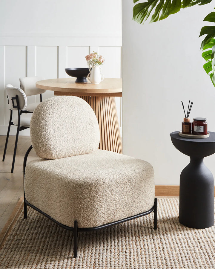 Beige armchair in a modern interior setting with a table and plants.