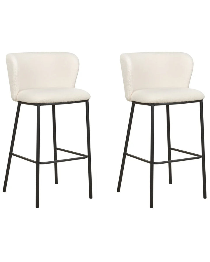 Two matching bar stools with cream upholstered seats and curved backs on black metal legs, shown against a plain white background.