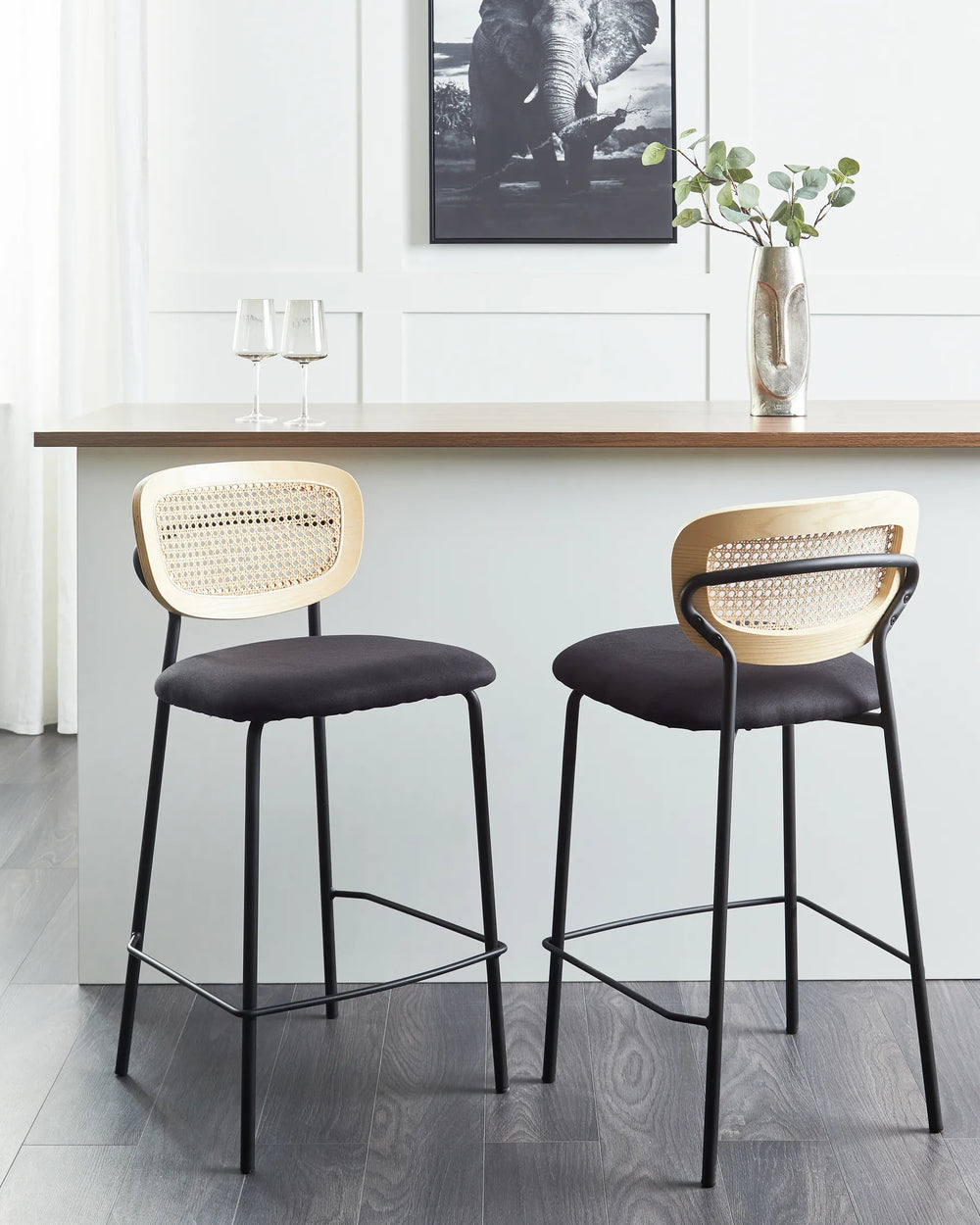 Two bar stools with woven backrests and black seats in a modern kitchen setting.