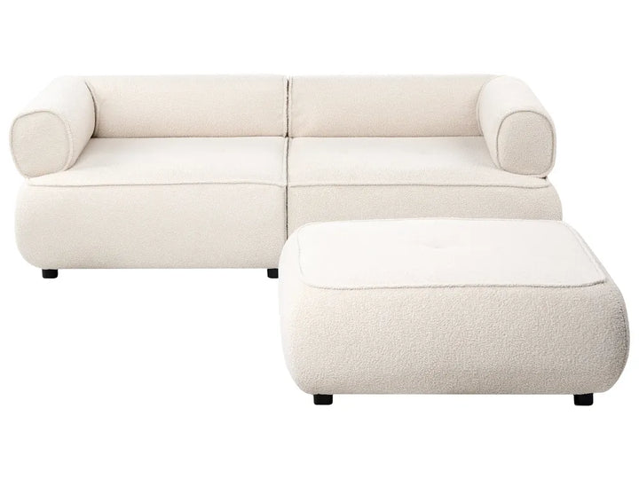 A modern modular upholstered sofa in a warm off-white fabric, paired with a matching square ottoman, shown against a solid white background.