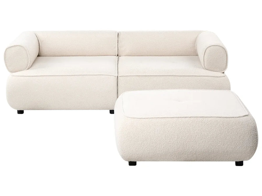 A modern modular upholstered sofa in a warm off-white fabric, paired with a matching square ottoman, shown against a solid white background.