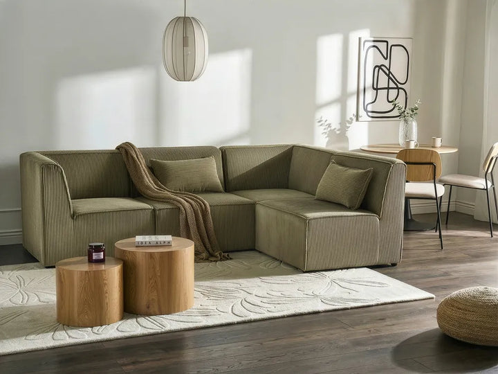 Modern living room with a beige sectional sofa, wooden coffee table, and decorative rug.