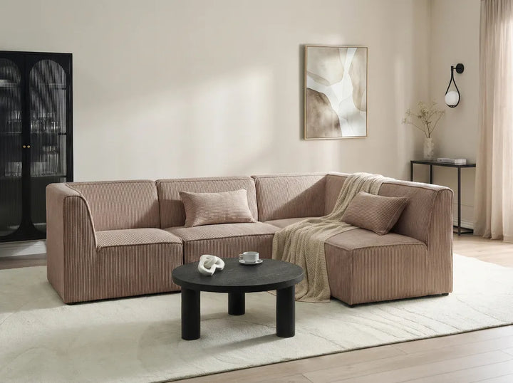 Beige sectional sofa in a living room setting with a coffee table and decorative items.