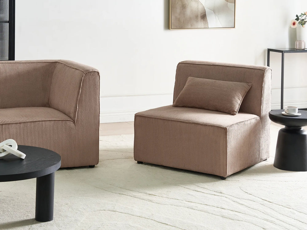 Modern living room with beige sofa and armchair, black coffee table, and decorative elements.