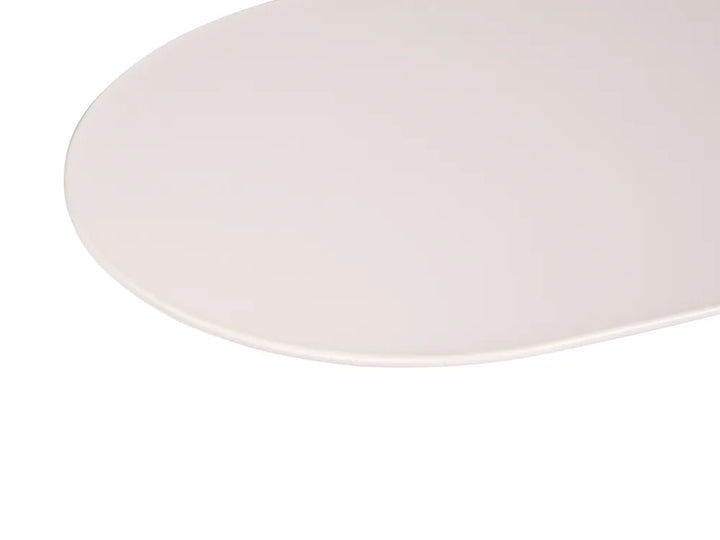 A close-up of a smooth, light beige oval surface, likely a tabletop or mat, against a solid white background.