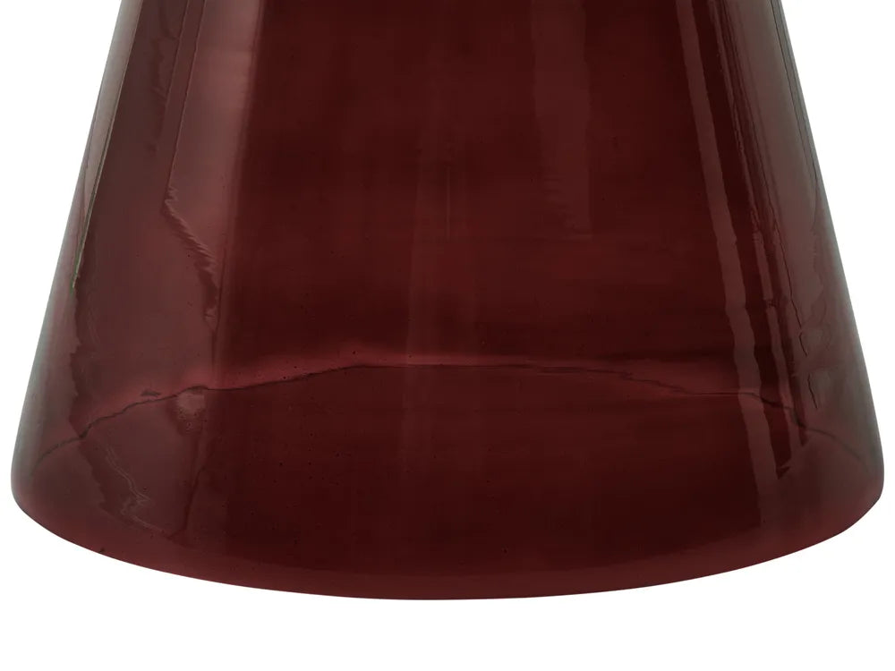 A close-up of a translucent dark burgundy glass shade or vase against a plain white background.