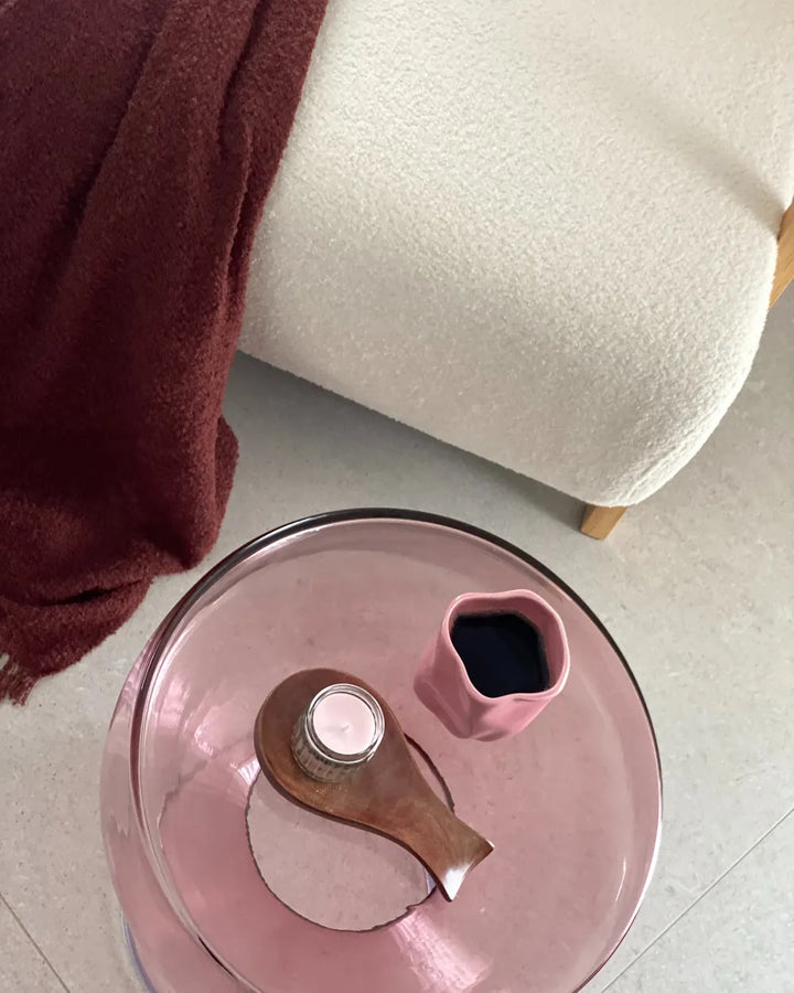 Pink pressure cooker lid with wooden handle on a tiled floor