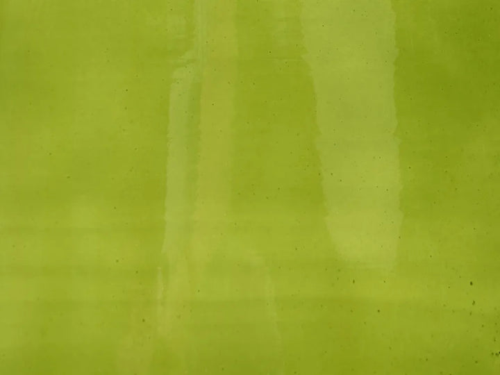 A close-up of a textured lime green surface with subtle vertical reflections and speckles.