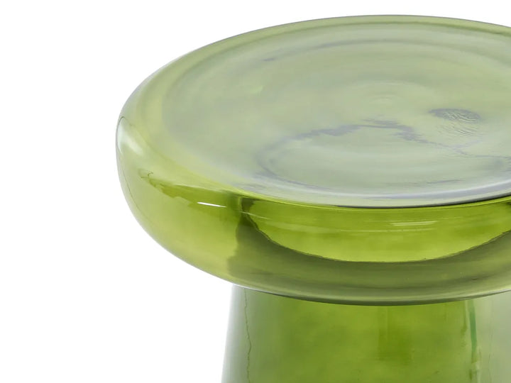 Close-up of a translucent light green glass stool or pedestal with a thick circular top and smooth curved base, photographed against a white background.