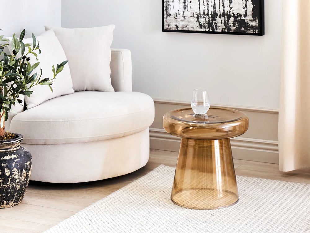 Modern living room with a white armchair, glass table, and decorative elements.