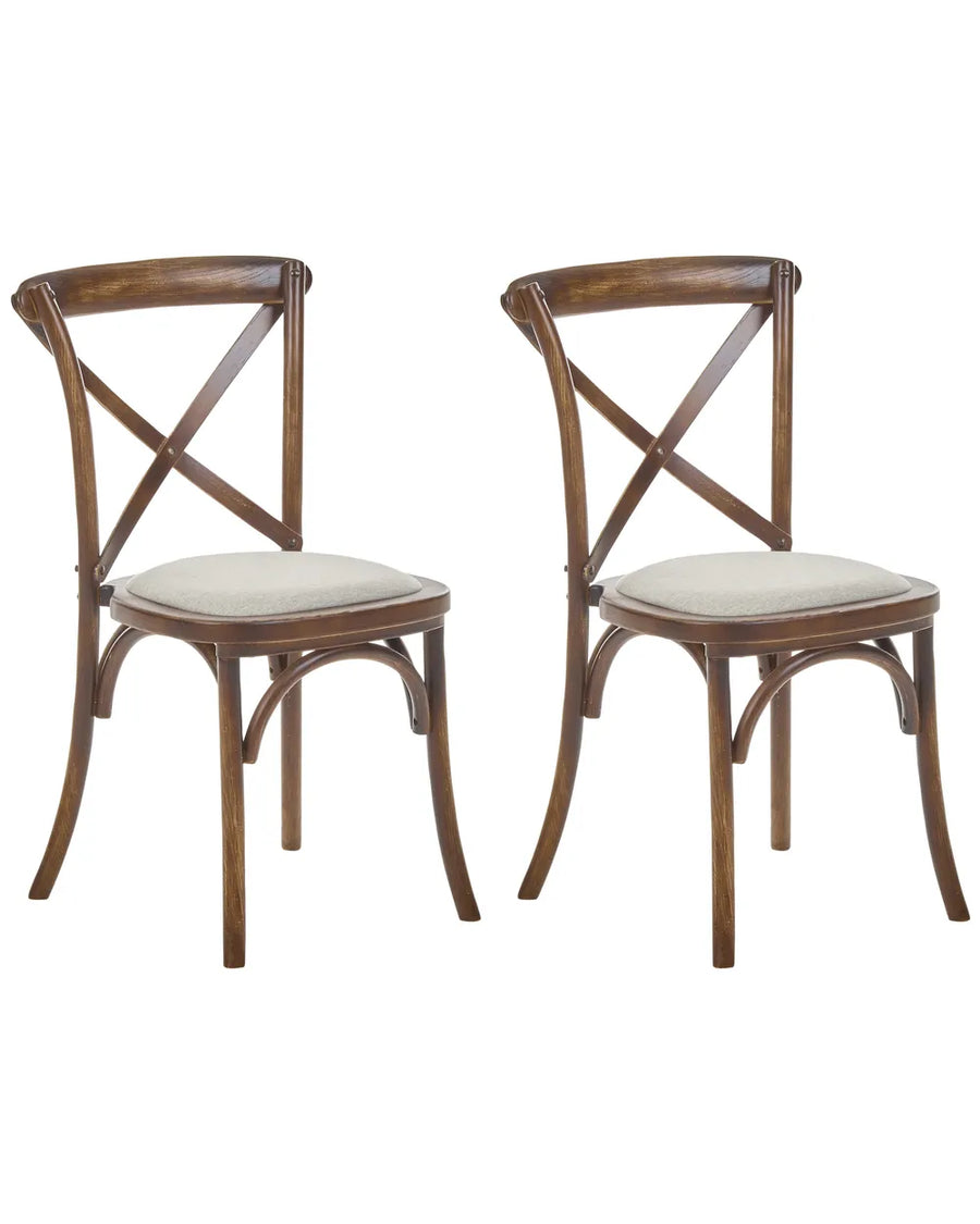 Two wooden dining chairs with curved backrests, crossed X-backs, and light beige upholstered seats, shown on a plain white background.