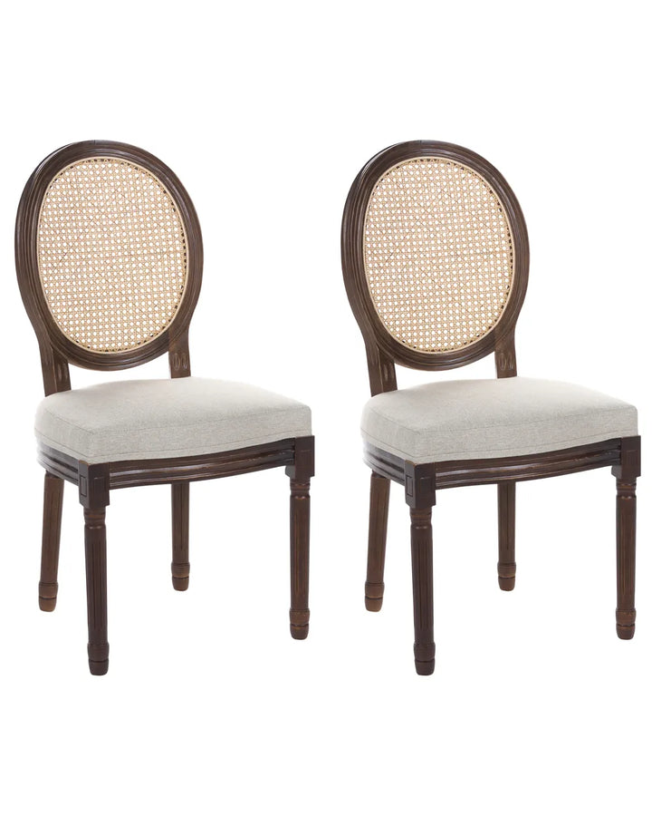 Two matching dining chairs with dark brown wooden frames, oval woven cane backrests, and light beige upholstered seats, shown on a plain white background.