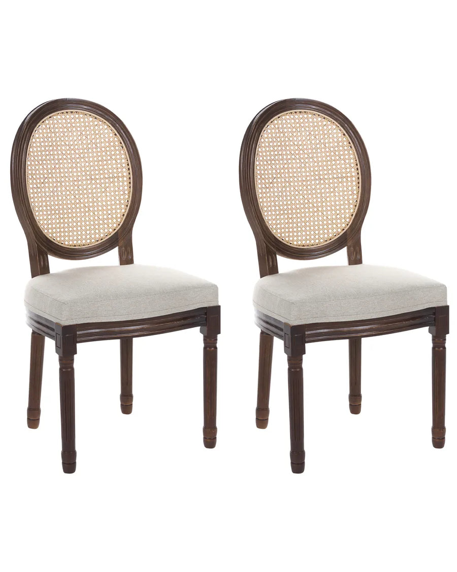 Two matching dining chairs with dark brown wooden frames, oval woven cane backrests, and light beige upholstered seats, shown on a plain white background.