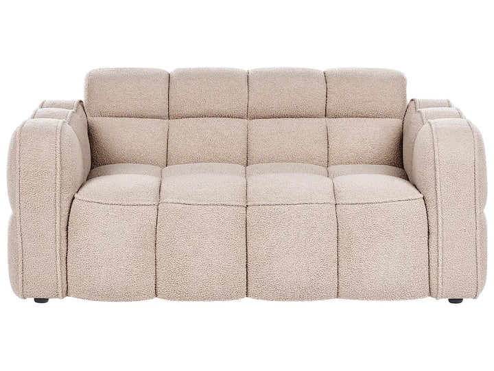 A modern three-seater sofa with a chunky, tufted block design and textured boucle-style upholstery in a light beige color, shown against a plain white background.